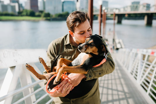Man in a brown jacket hugging his dog before a trip